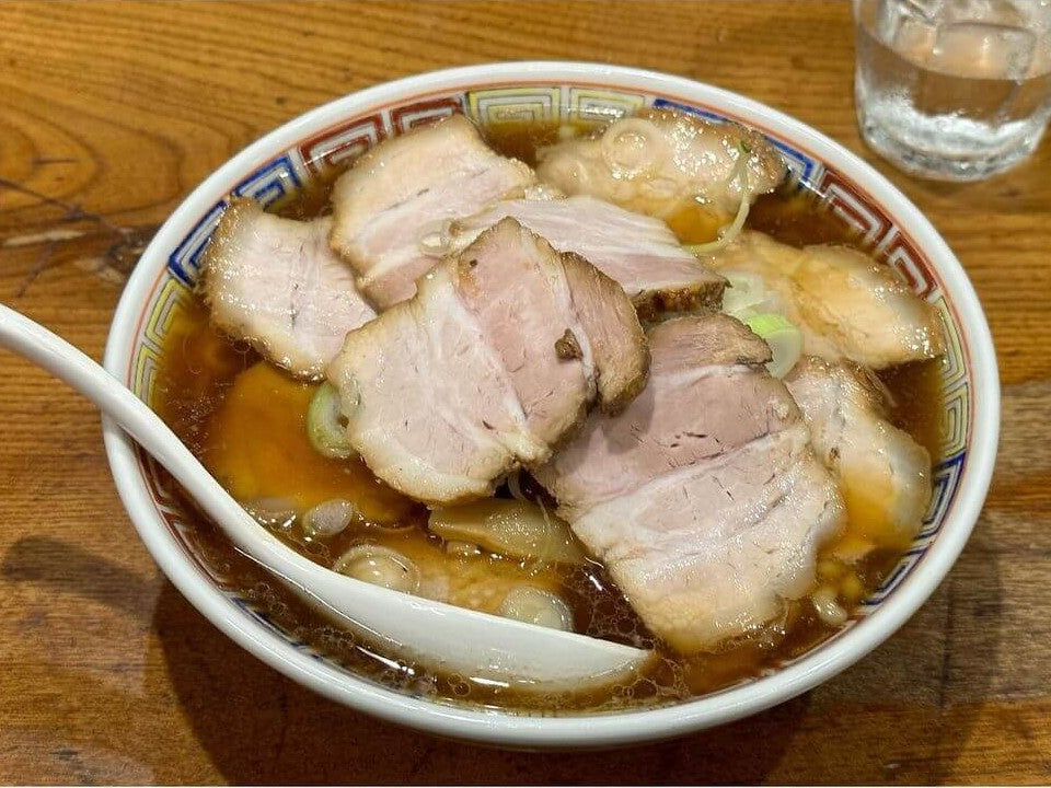 A bowl of Kitakata ramen with a brown broth and plenty of pork on top