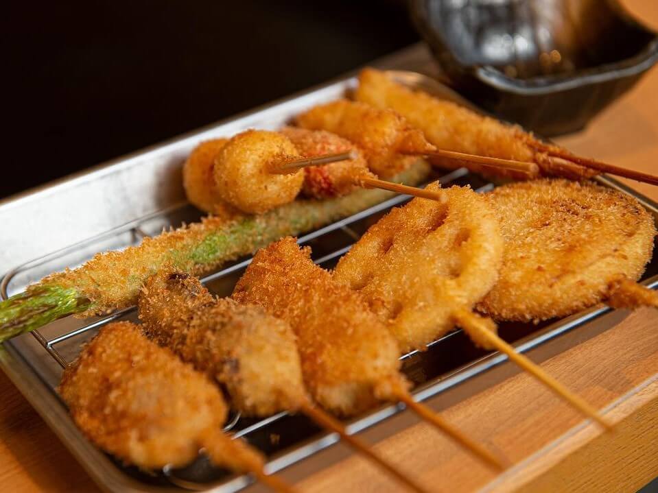 A tray of various kushikatsu with food like asparagus, lotus root and mushroom