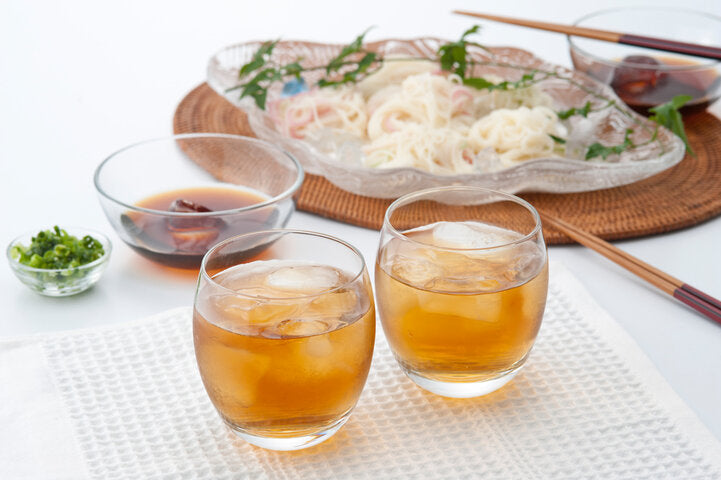 Cups of cold tea sit in front of cold noodles and a bowl of tsuyu dipping sauce