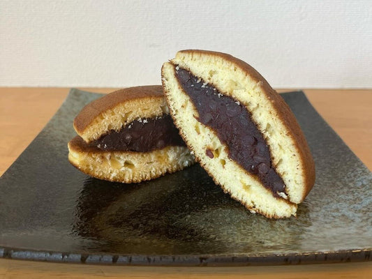 A dorayaki over a plate cut in half to show the castella and red bean layers
