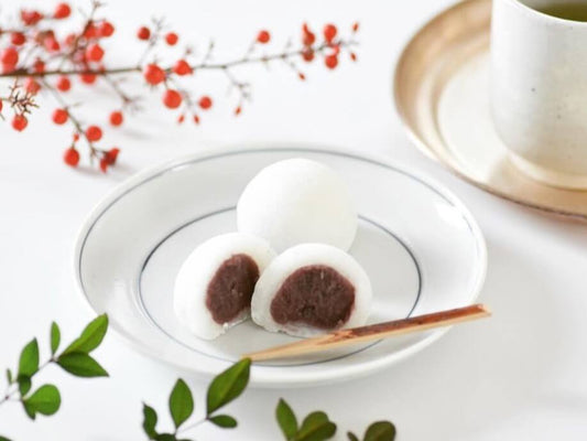 A plate with a couple of mini daifuku with one cut in half to show the red bean paste