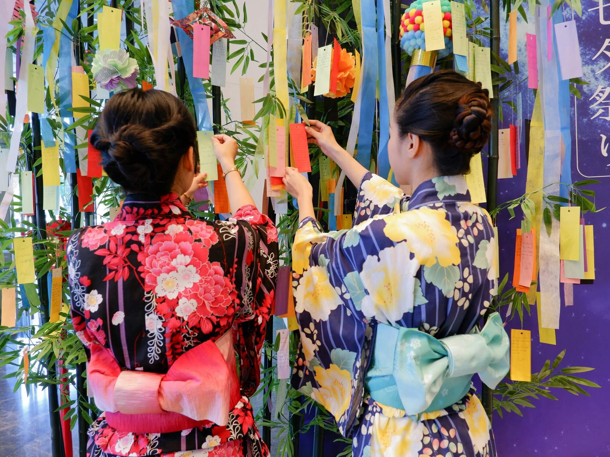 Two women hang their wishes on Tanabata wish trees