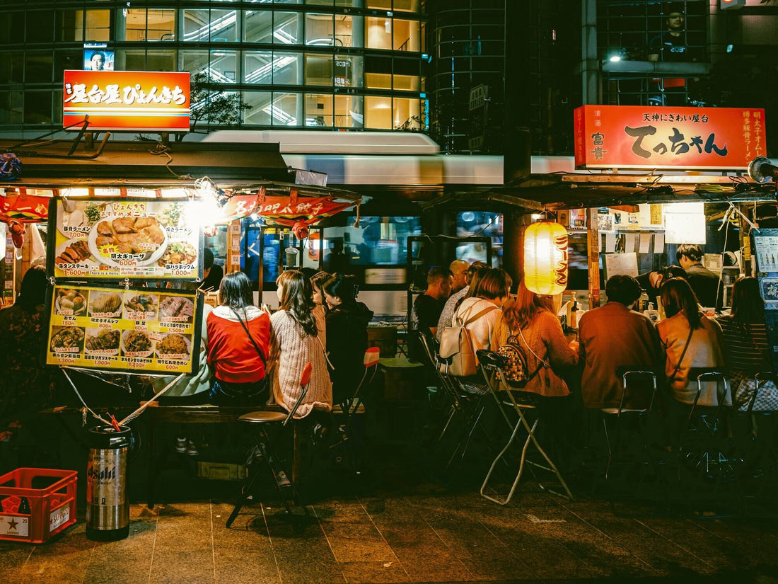 Many people sit around Japanese street food stalls in Fukuoka