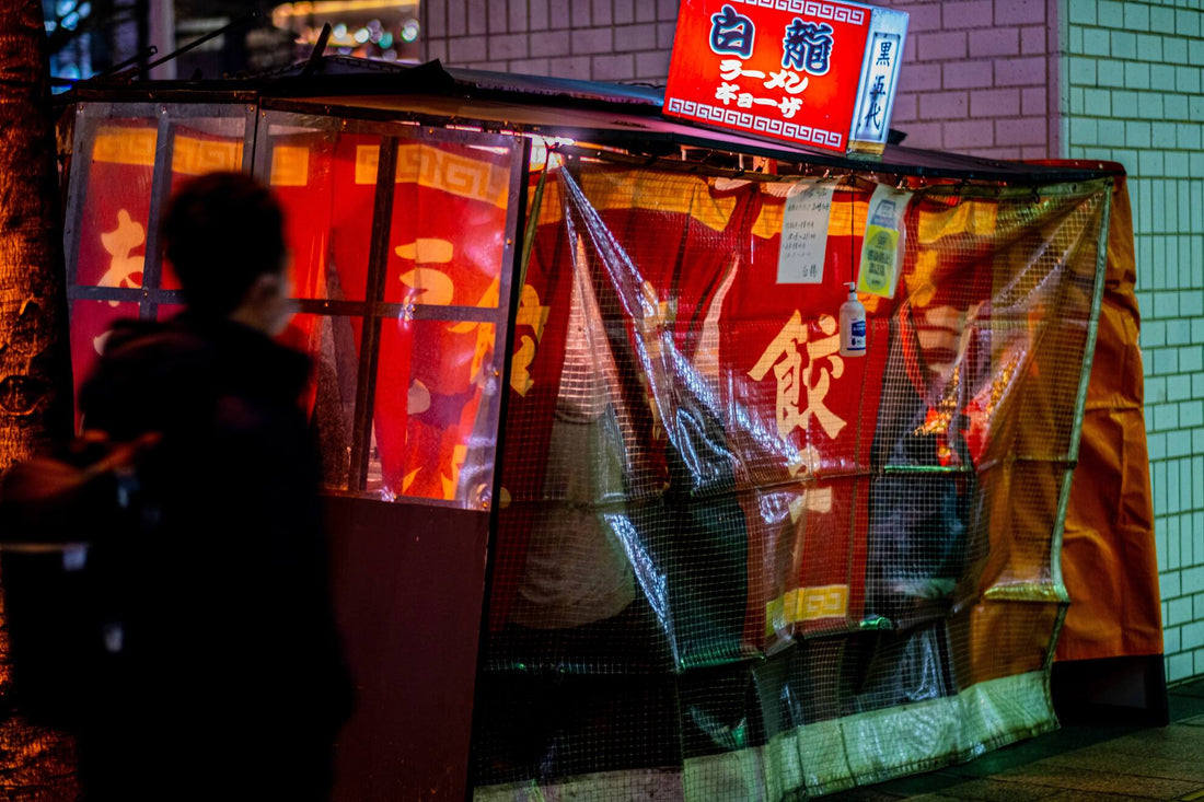 A Japanese yatai food stall with people a cover has people sitting under it